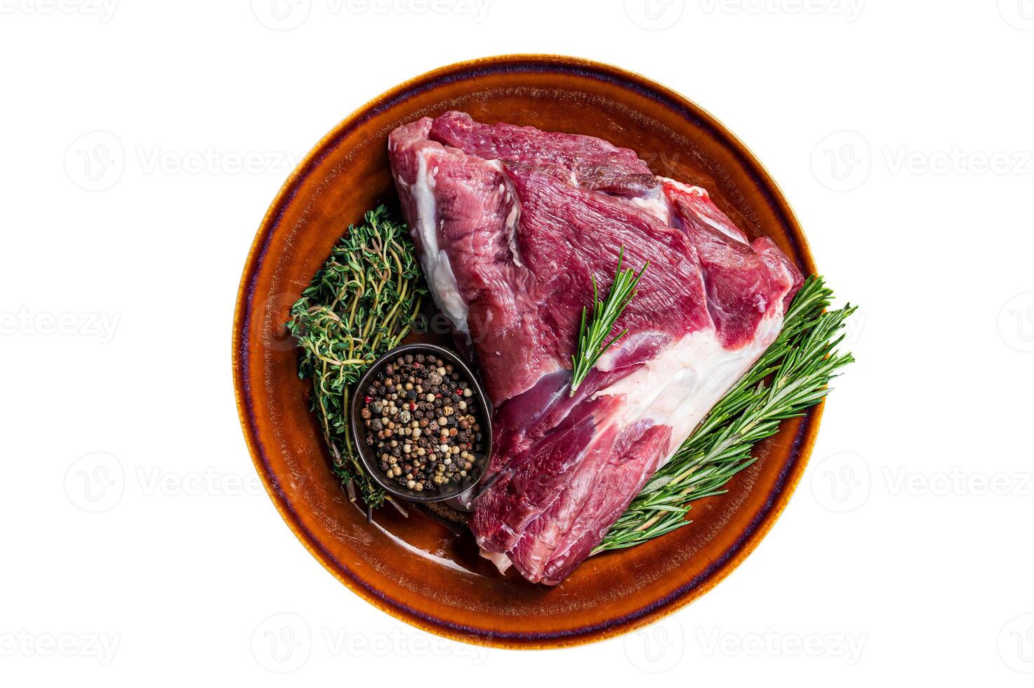 Uncooked Raw goat thigh or leg with rosemary and thyme in rustic plate. Isolated on white background. photo