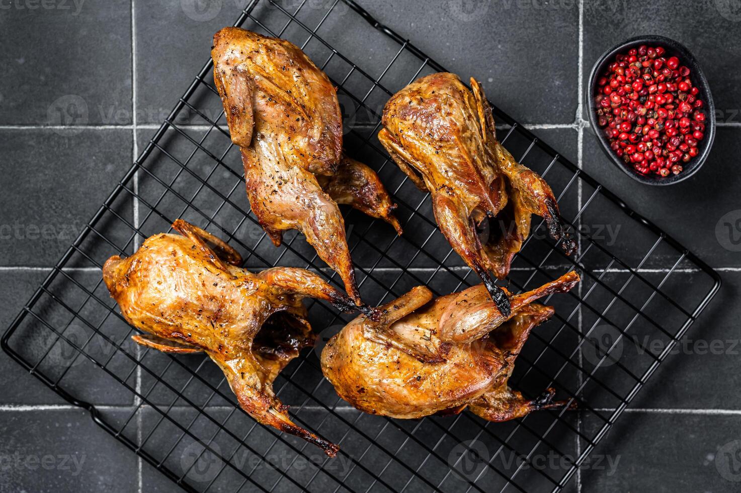 Grilled whole quails with herbs and spices. Black background. Top view photo