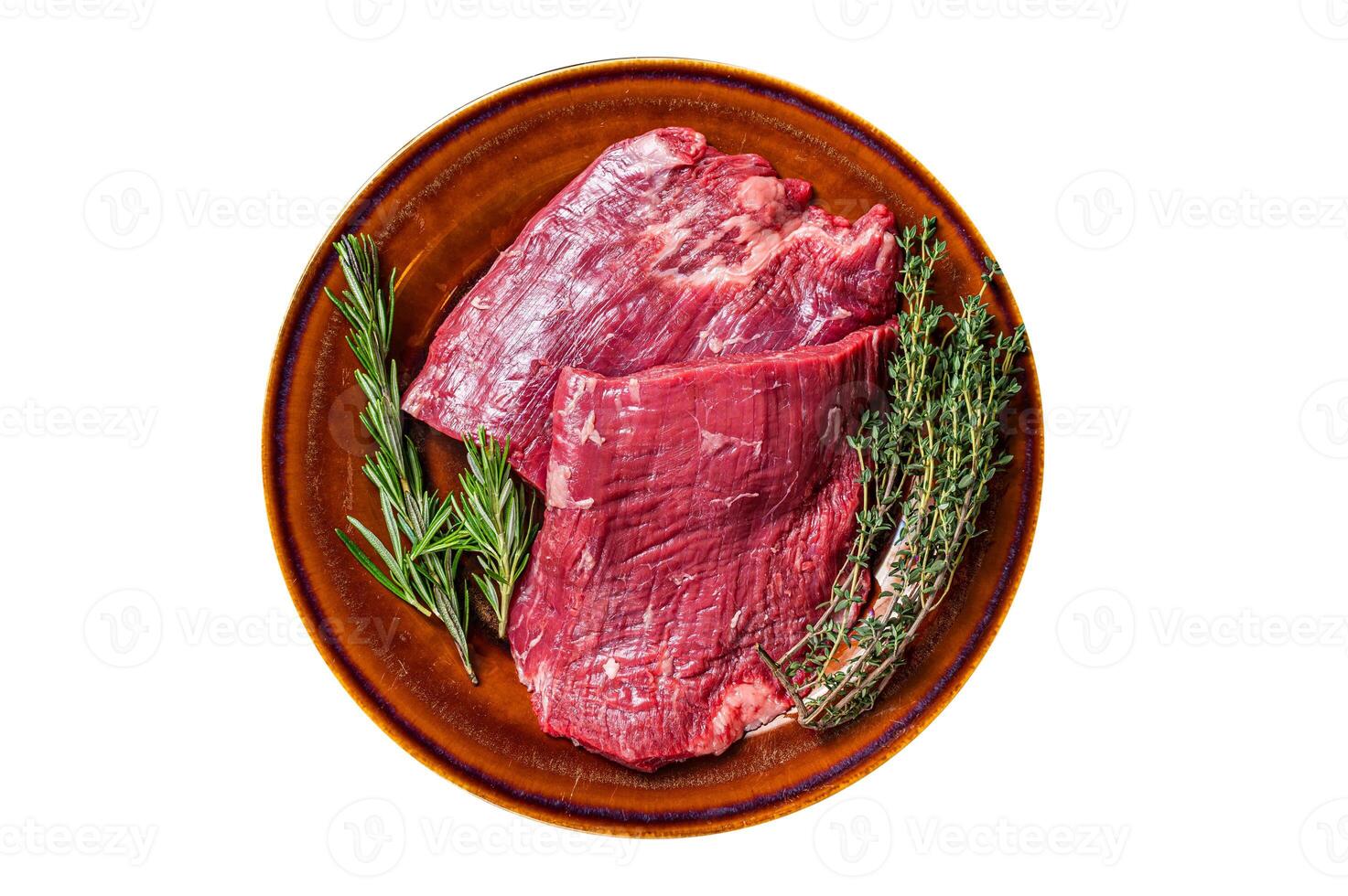 Two Flap or Flank raw beef steaks on a rustic plate with herbs. Isolated, white background. Top view. photo