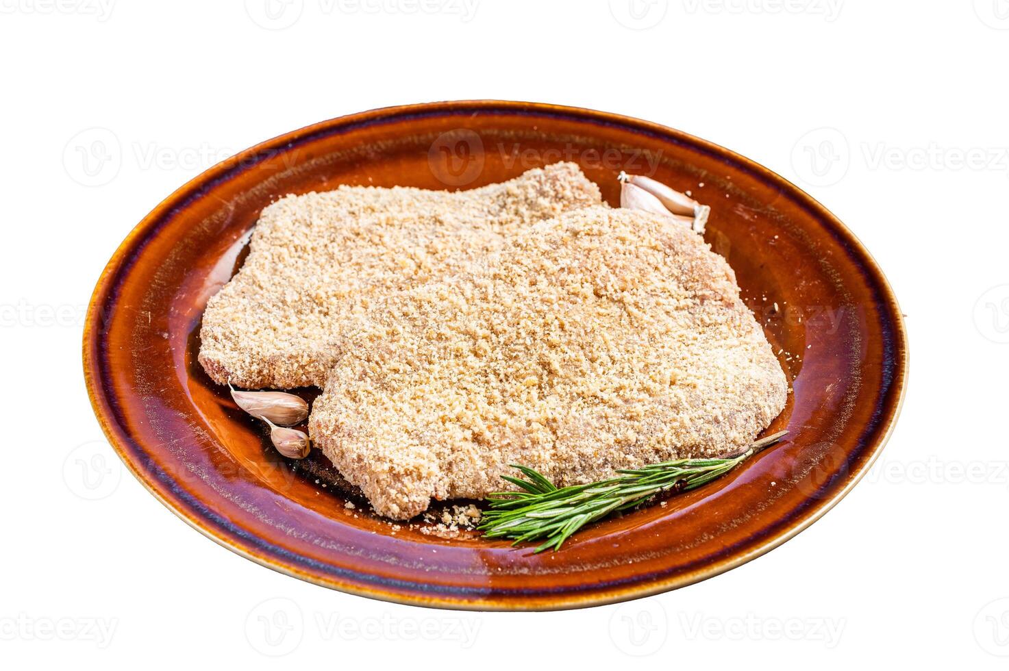 Raw Breaded German Wiener schnitzel on a rustic plate with herbs. Isolated on white background. photo