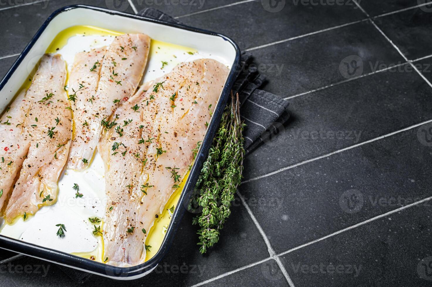 Marinated ocean red perch fillet with olive oil, thyme and spices. Black background. Top view. Copy space photo