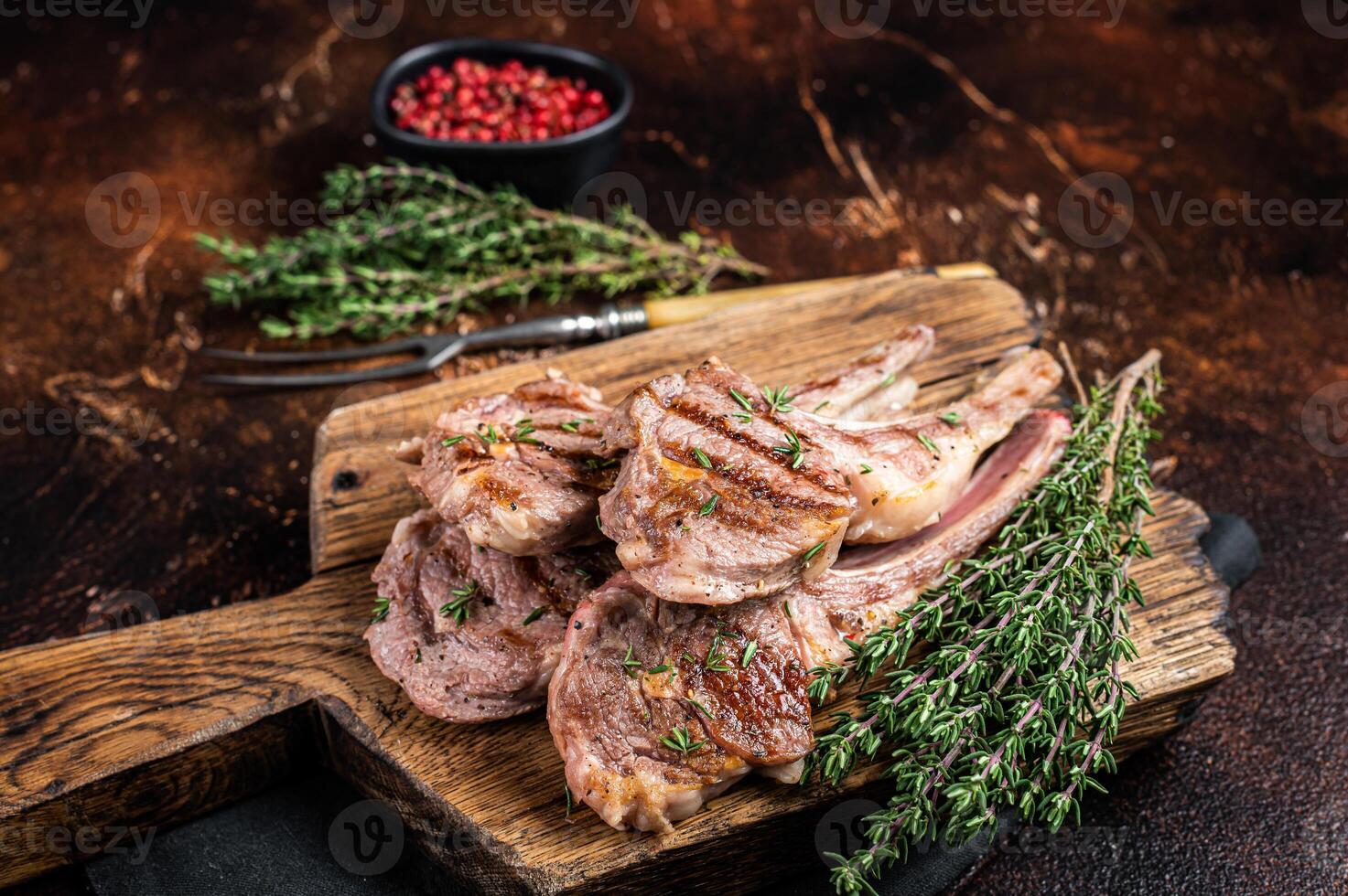 Grilled New Zealand Lamb Chops, mutton cutlets on wooden board. Dark background. Top view photo
