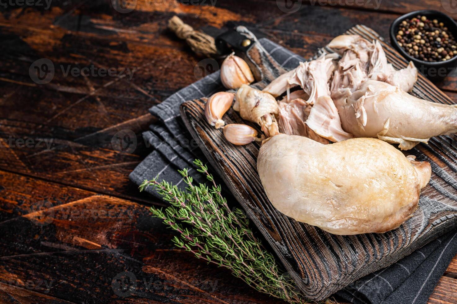 Boiled chicken leg thigh on a wooden board with herbs. Wooden background. Top view. Copy space photo