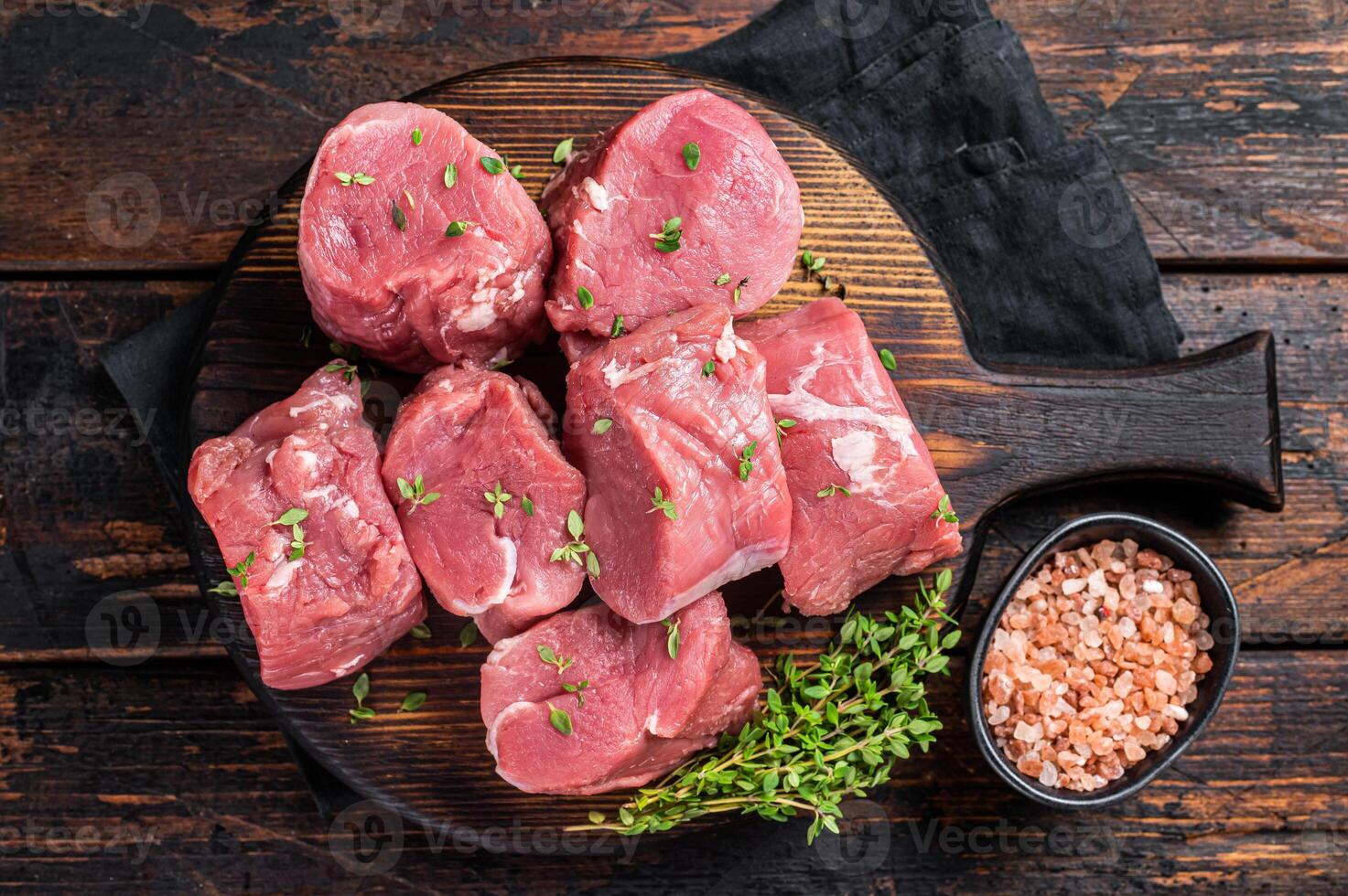 Raw pork sliced tenderloin fillet meat for medallions steaks on a wooden cutting board. Wooden background. Top view photo
