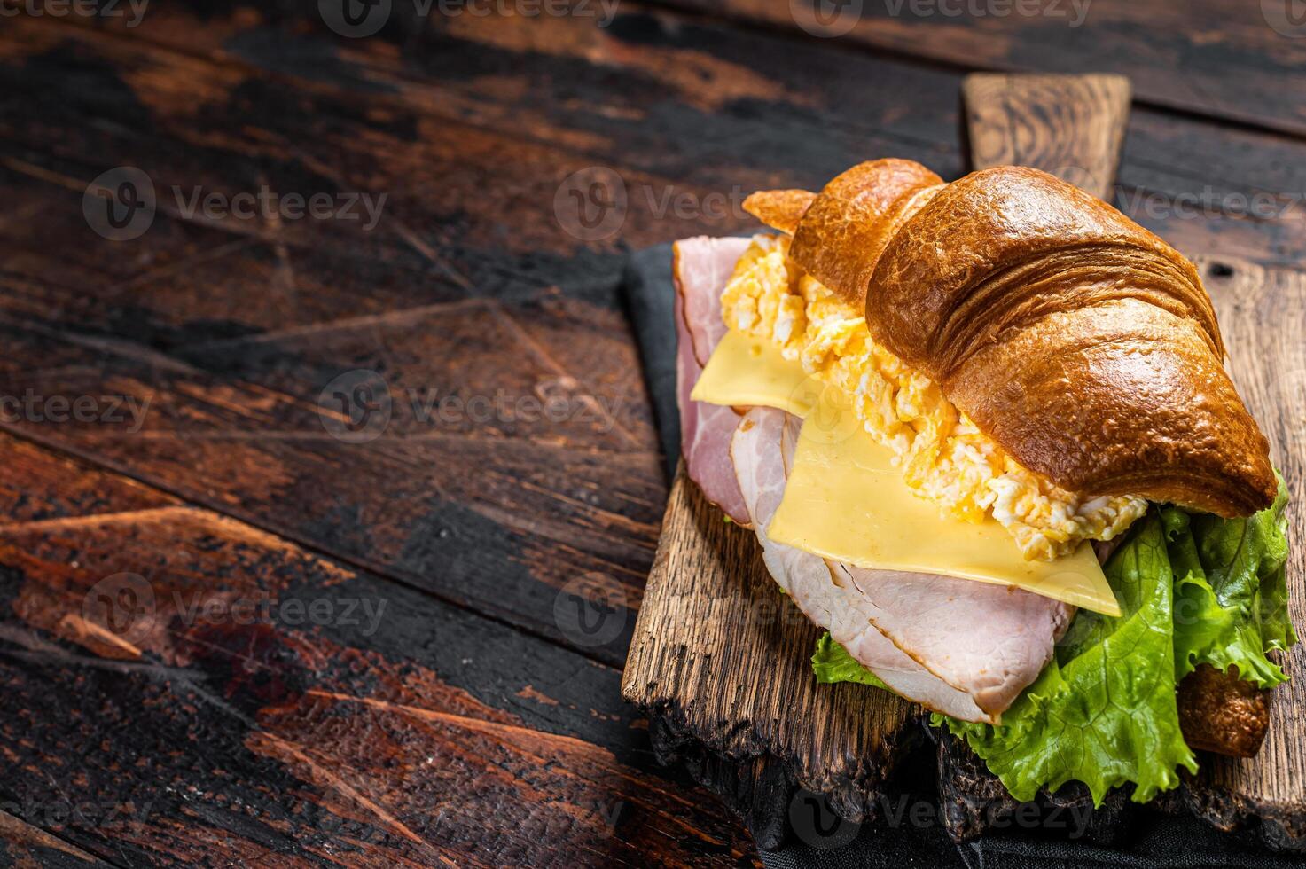 Croissant sandwich with egg cheese and green lettuce salad leaf, healthy breakfast. Wooden background. Top view. Copy space photo