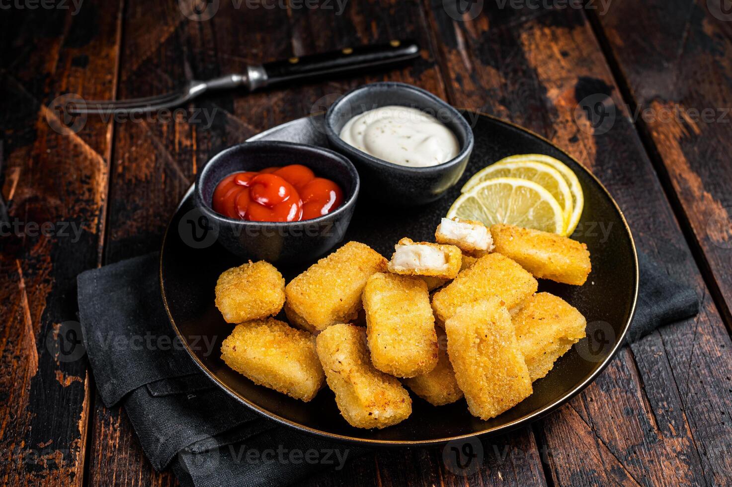 Fried Fish Sticks Fingers with sauce in a plate. Wooden background. Top view photo
