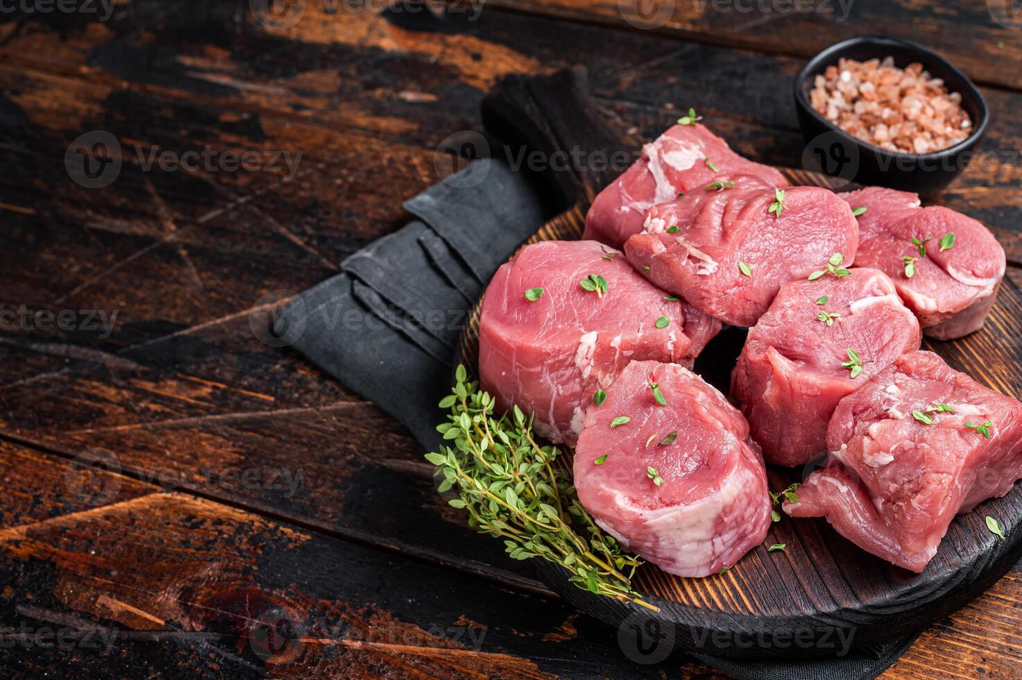 Raw pork sliced tenderloin fillet meat for medallions steaks on a wooden cutting board. Wooden background. Top view. Copy space photo