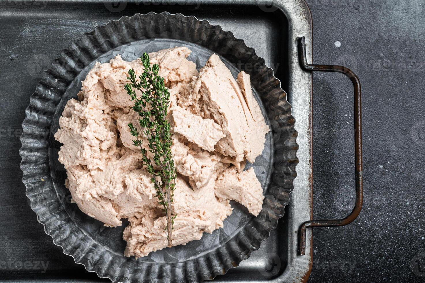 Canned Cod liver with thyme in oil on plate. Black background. Top view photo