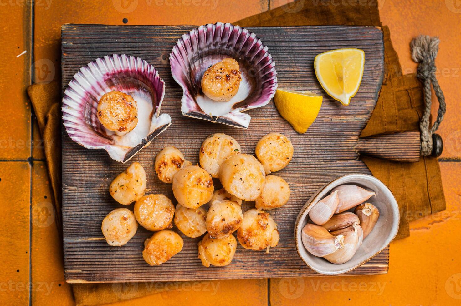 Seared Scallops fillets on a wooden board ready for eat. Orange background. Top view photo