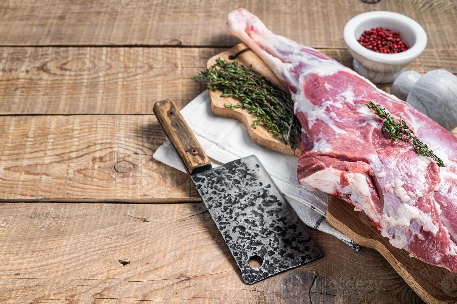 Butcher board with Raw lamb mutton leg with herbs. Wooden background. Top view. Copy space photo