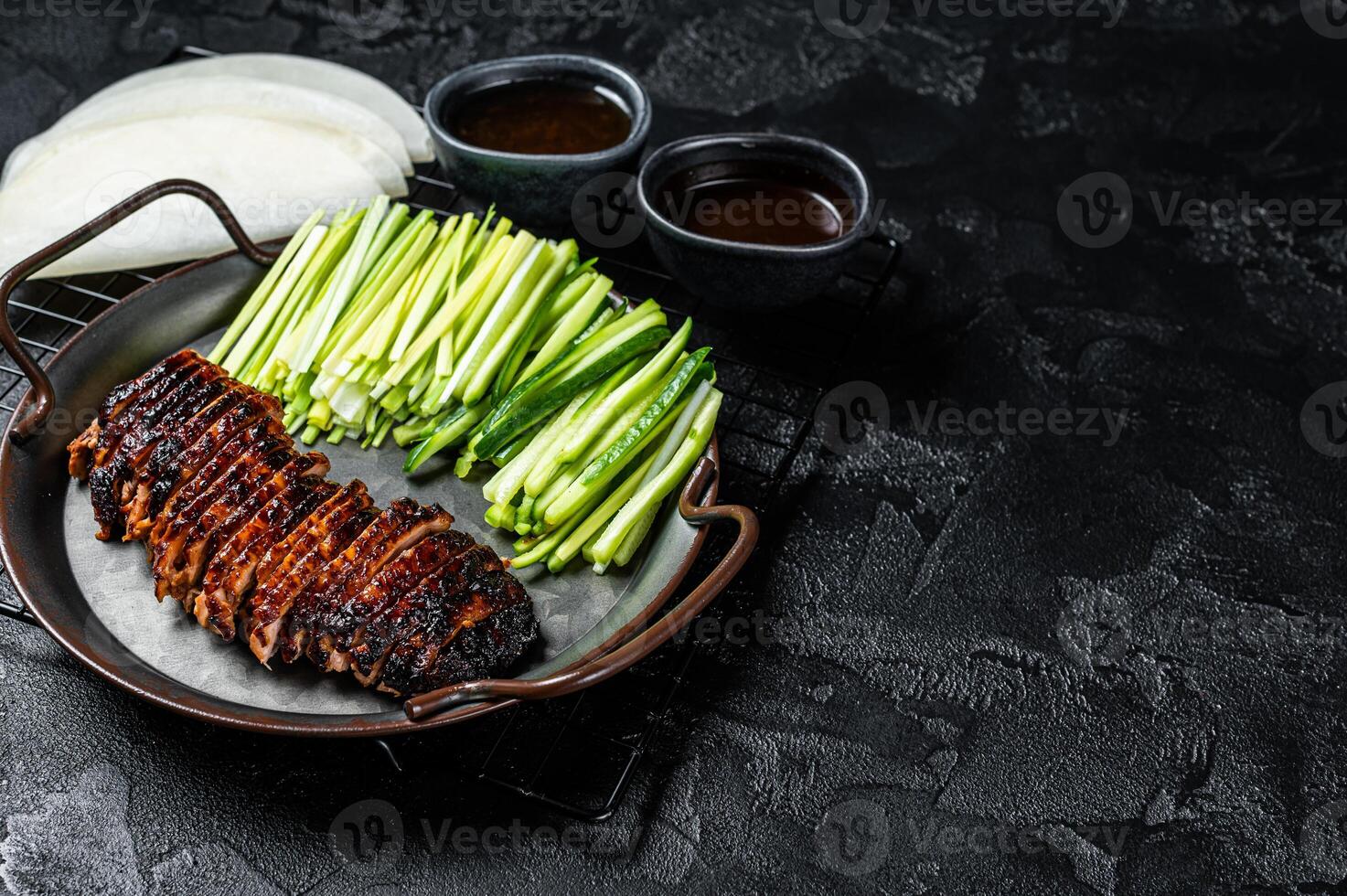 Peking Duck served with cucumber, green onions, and roasted wheaten chinese pancakes with sauce Hoysin. Black background. Top view. Copy space photo