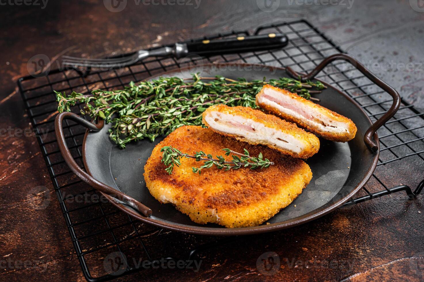 Cordon bleu chicken fillet cutlet with ham and cheese. Dark background. Top view photo