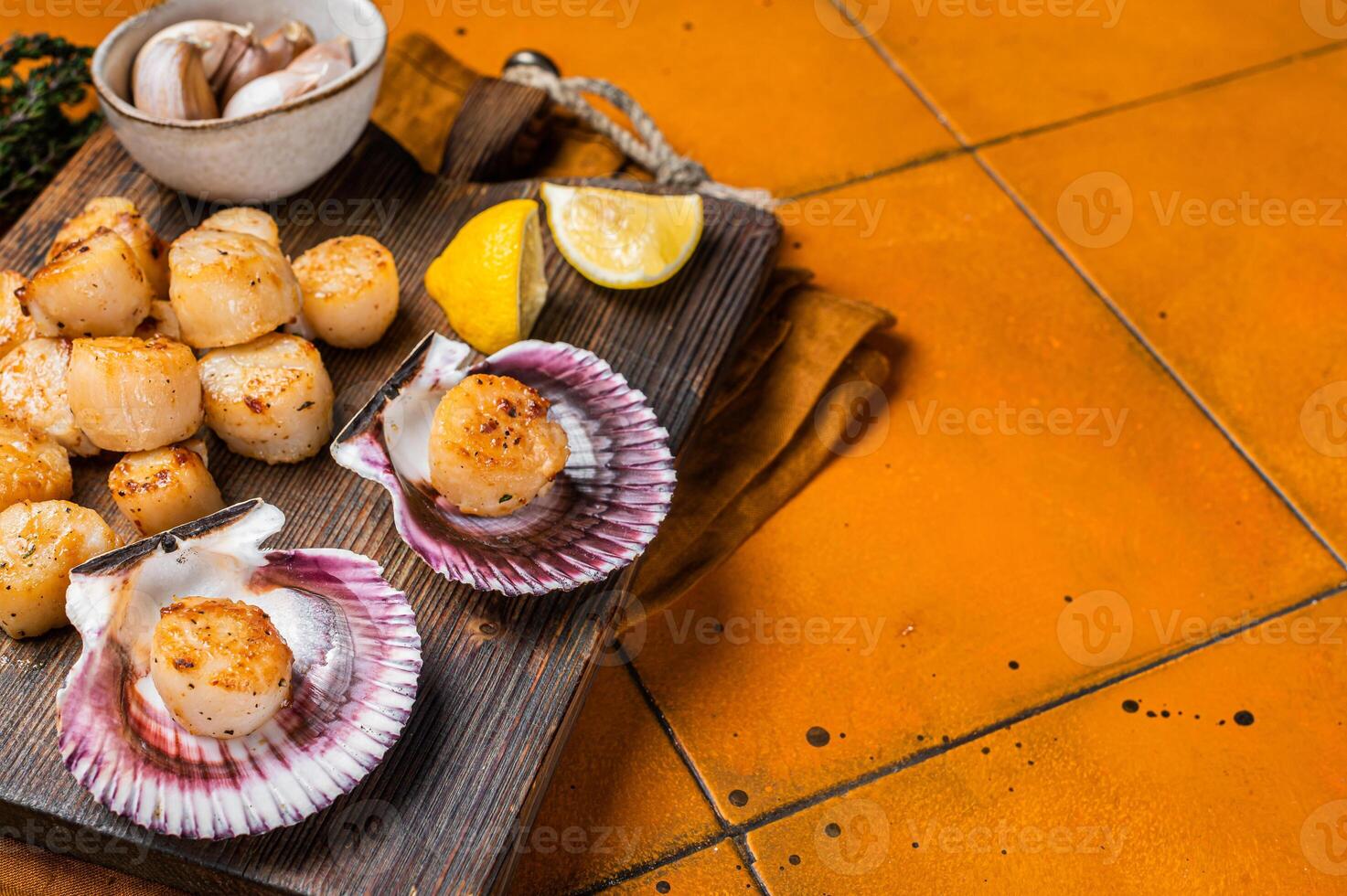 Seared Scallops fillets on a wooden board ready for eat. Orange background. Top view. Copy space photo