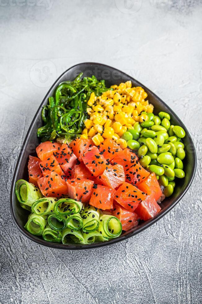Salmon Poke bowl with Cucumber, Edamame, and Rice. White background. Top view photo