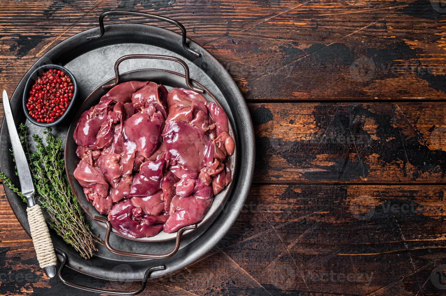 Fresh Raw chicken liver, poultry giblets in steel tray with herbs. Wooden background. Top view. Copy space photo