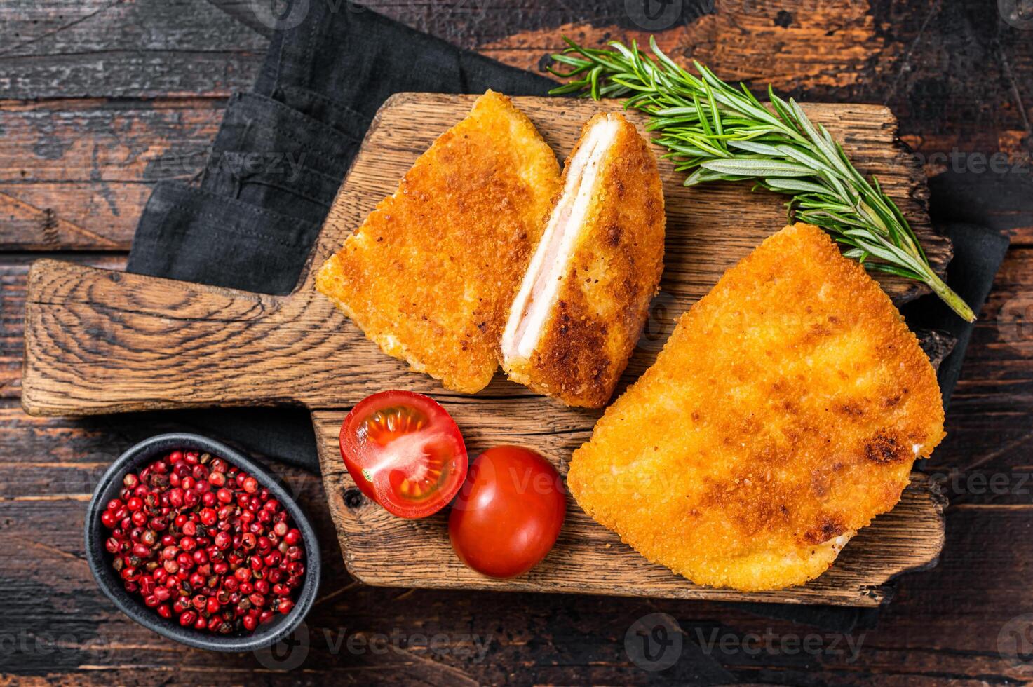 Crispy Cordon Blue Chicken fillet roll with ham and cheese served on a wooden board. Wooden background. Top view photo