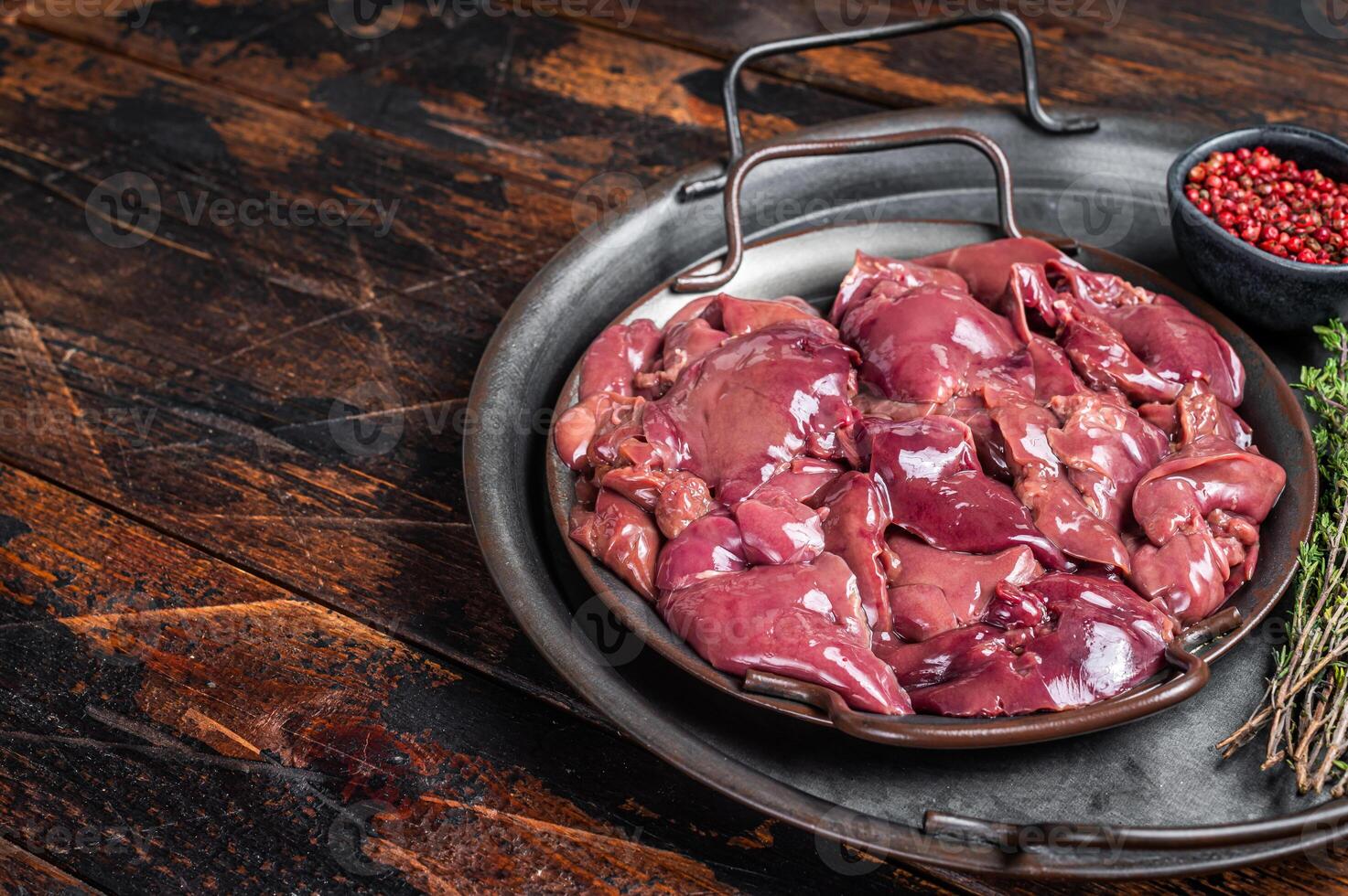 Fresh Raw chicken liver, poultry giblets in steel tray with herbs. Wooden background. Top view. Copy space photo