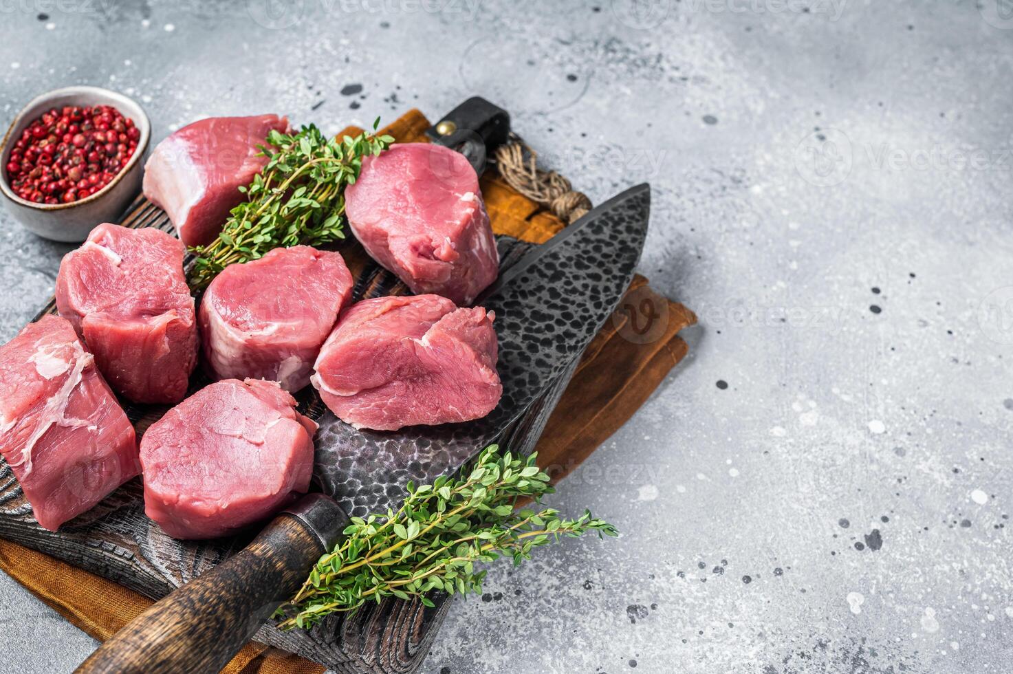 Fresh Raw pork tenderloin medallions steaks on a wooden cutting board. Gray background. Top view. Copy space photo