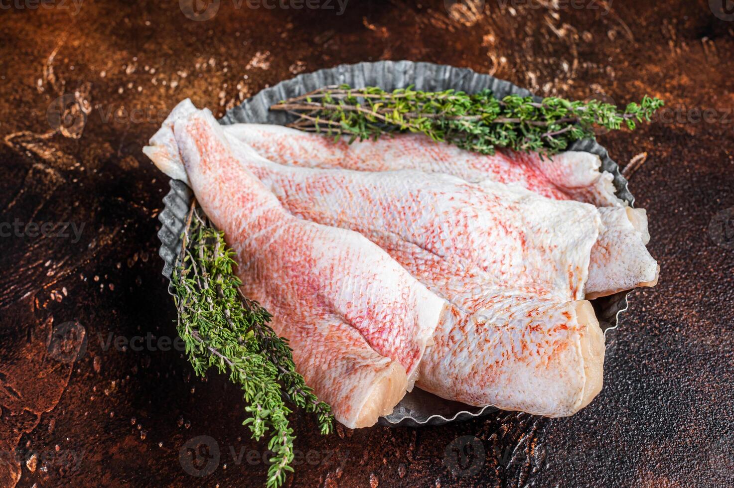 Raw ocean red perch fillet, Snapper fish with herbs. Dark background. Top view photo