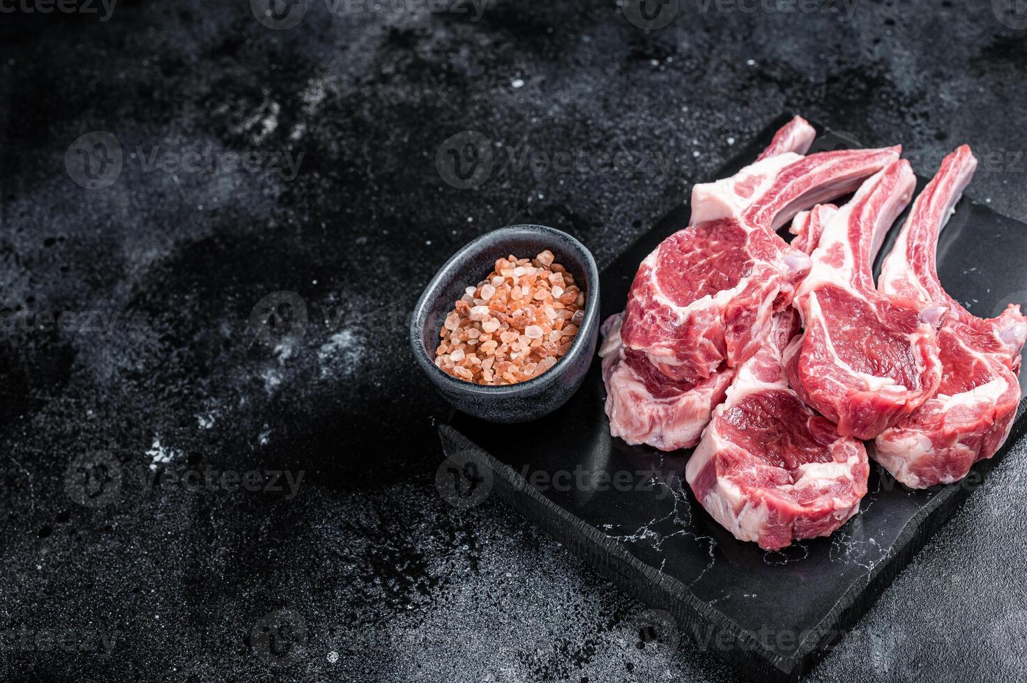 Uncooked lamb mutton chops, raw meat steaks. Black background. Top view. Copy space photo