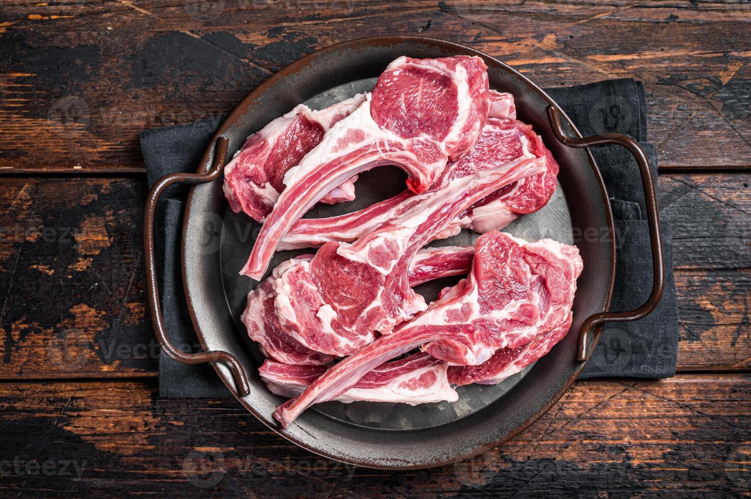Raw lamb mutton chop steaks, fresh meat cutlets on butcher table. Black background. Top view photo