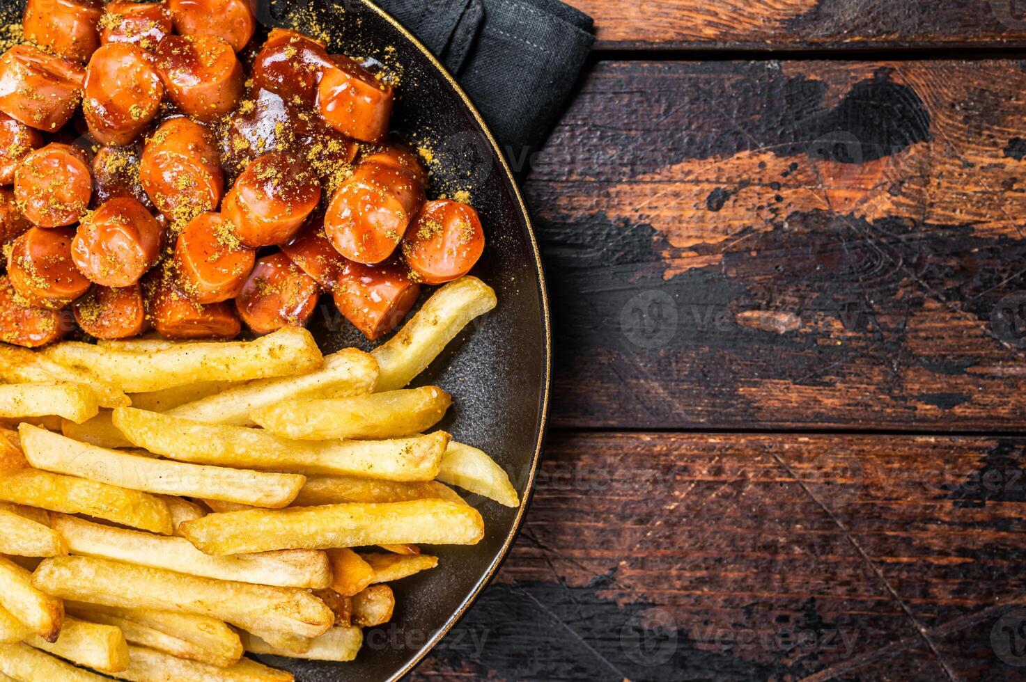 German currywurst meal, curry wurst with french fry served in a plate. Wooden background. Top view photo