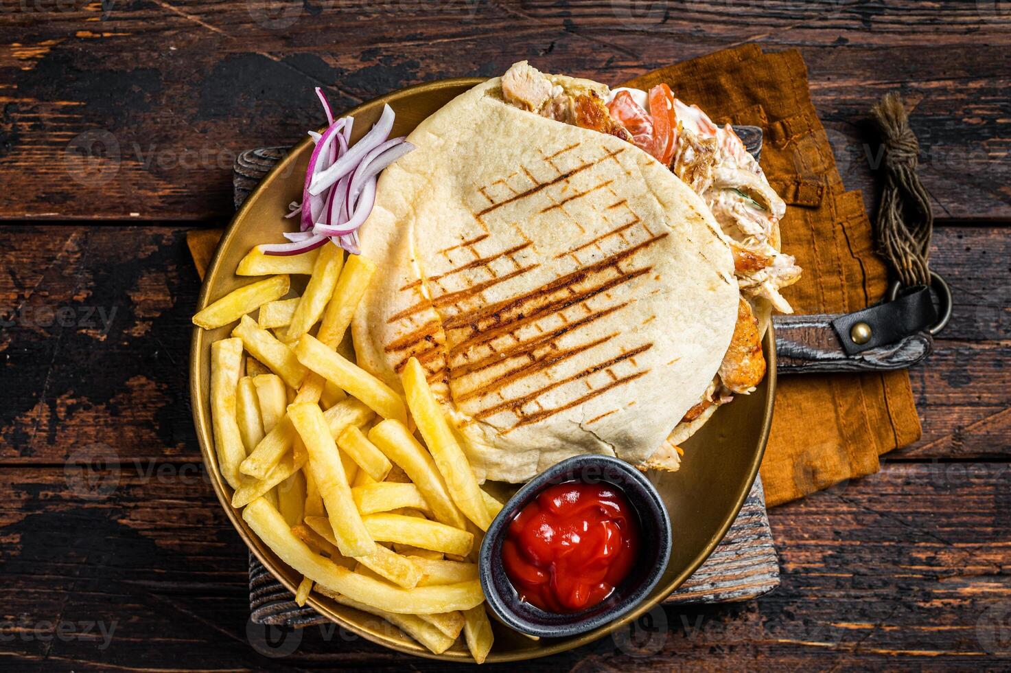 Doner kebab, Shawarma in grilled pita bread with vegetables, meat and french fry. Wooden background. Top view photo