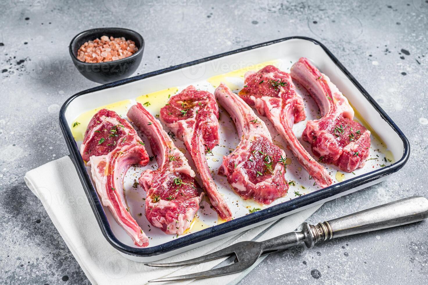 Ready for cooking raw lamb chop steaks with spices and herbs. Gray background. Top view photo