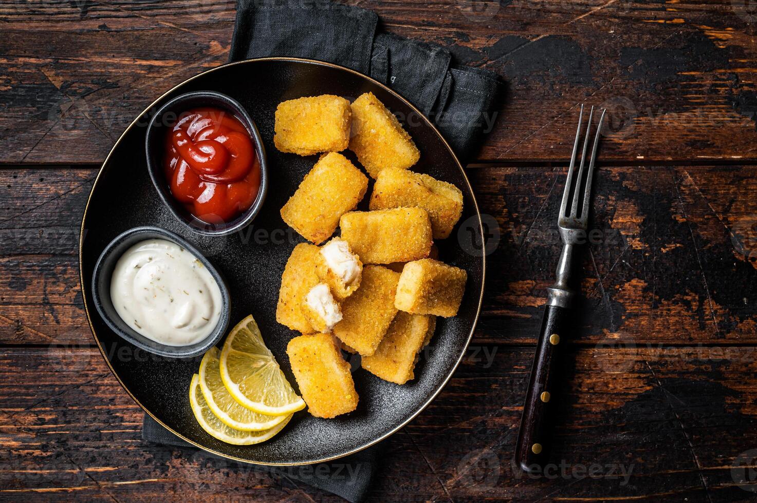Fried Fish Sticks Fingers with sauce in a plate. Wooden background. Top view photo