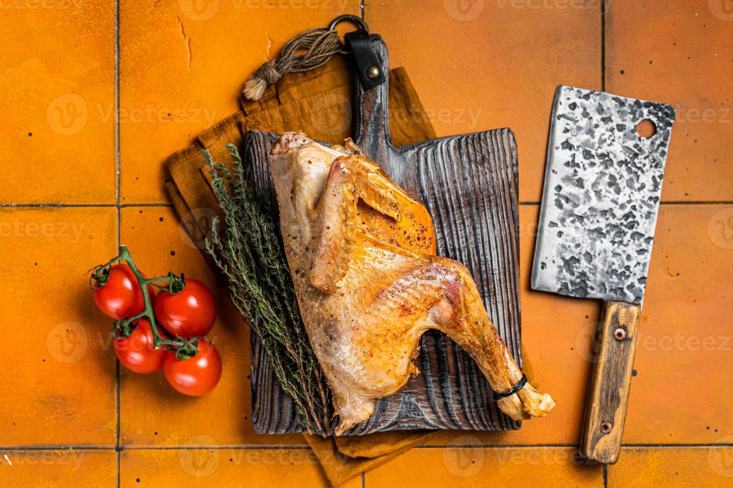 Grilled guinea fowl with herbs and spices on butcher board, cooked game bird. Orange background. Top view photo