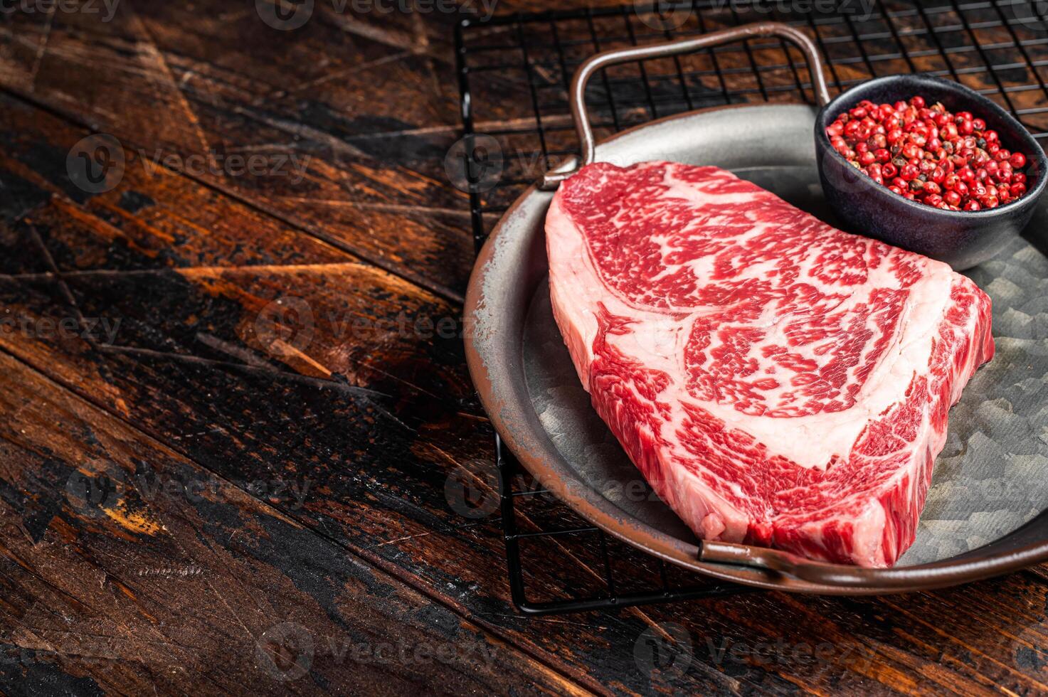 Raw wagyu rib eye beef meat steak in steel tray. Wooden background. Top view. Copy space photo