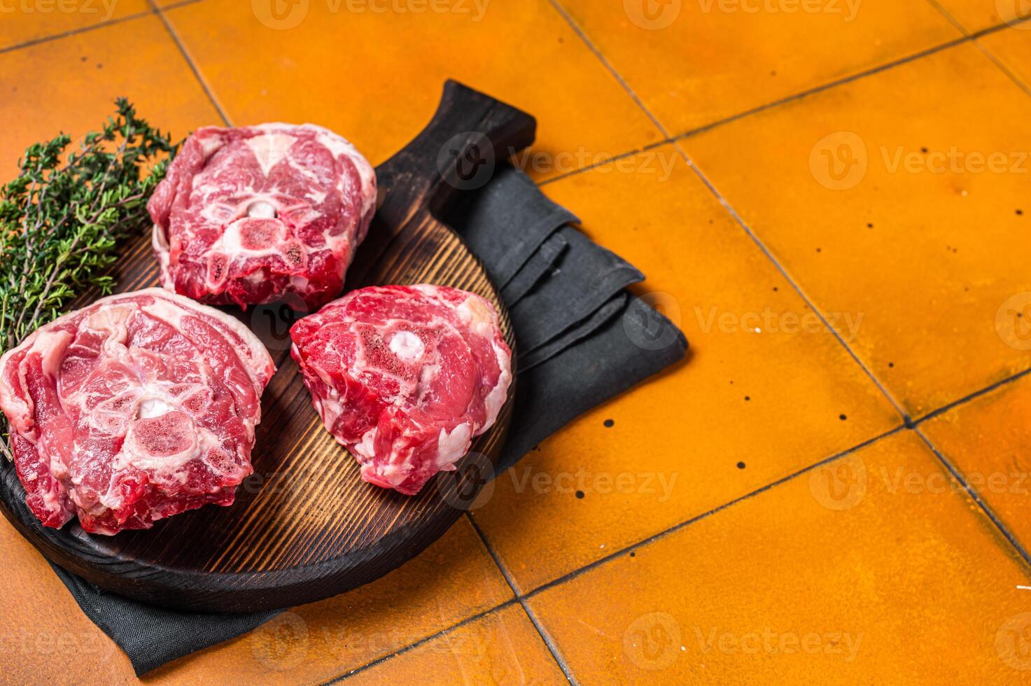Raw lamb neck chops, fresh mutton meat on a butcher board with herbs. Orange background. Top view. Copy space photo