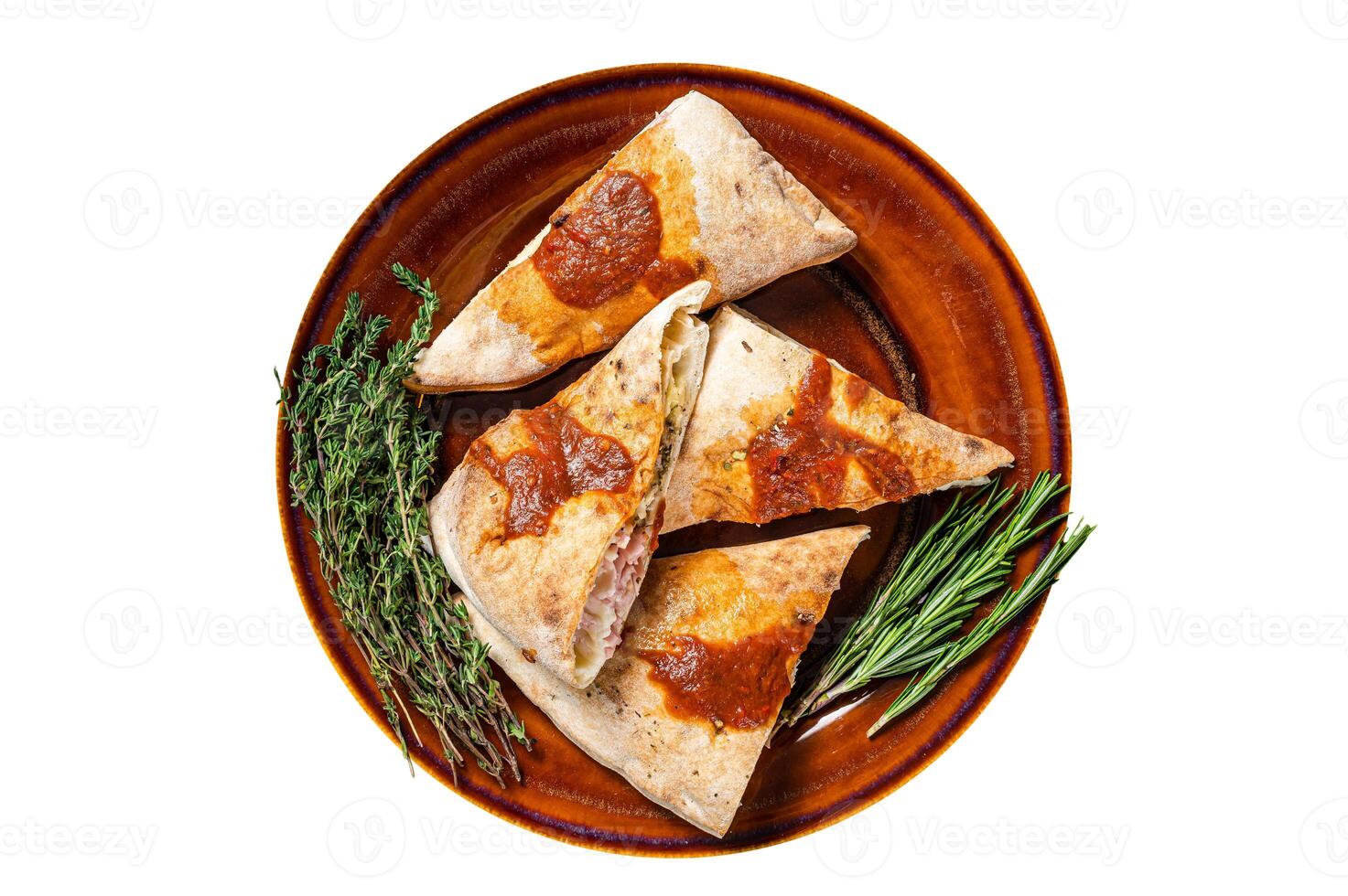 Calzone pizza pieces on rustic plate with tomato sauce and herbs. Isolated, white background. Top view. photo