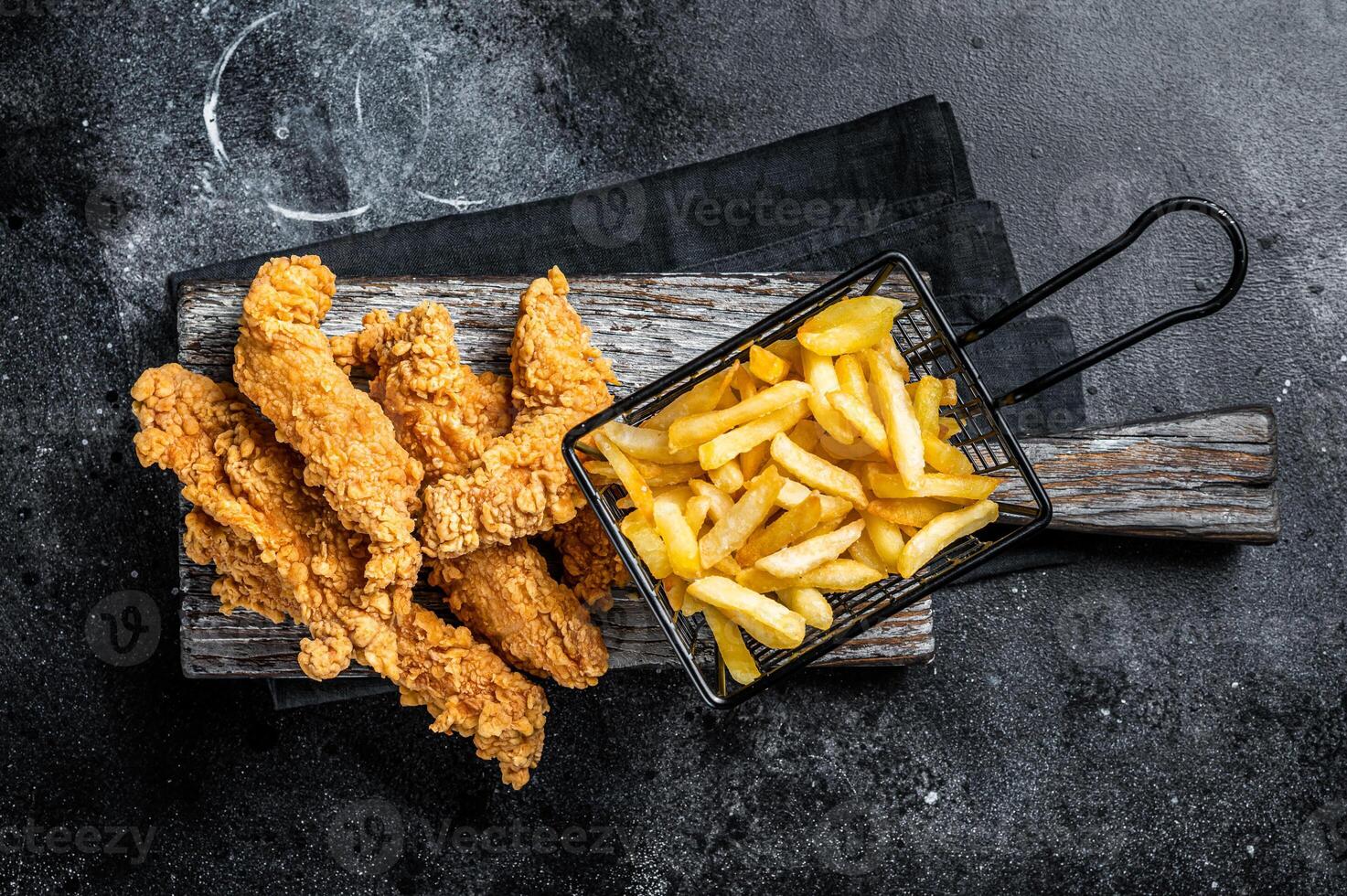 Chicken breast strips with French Fries and Ketchup. Black background. Top view photo