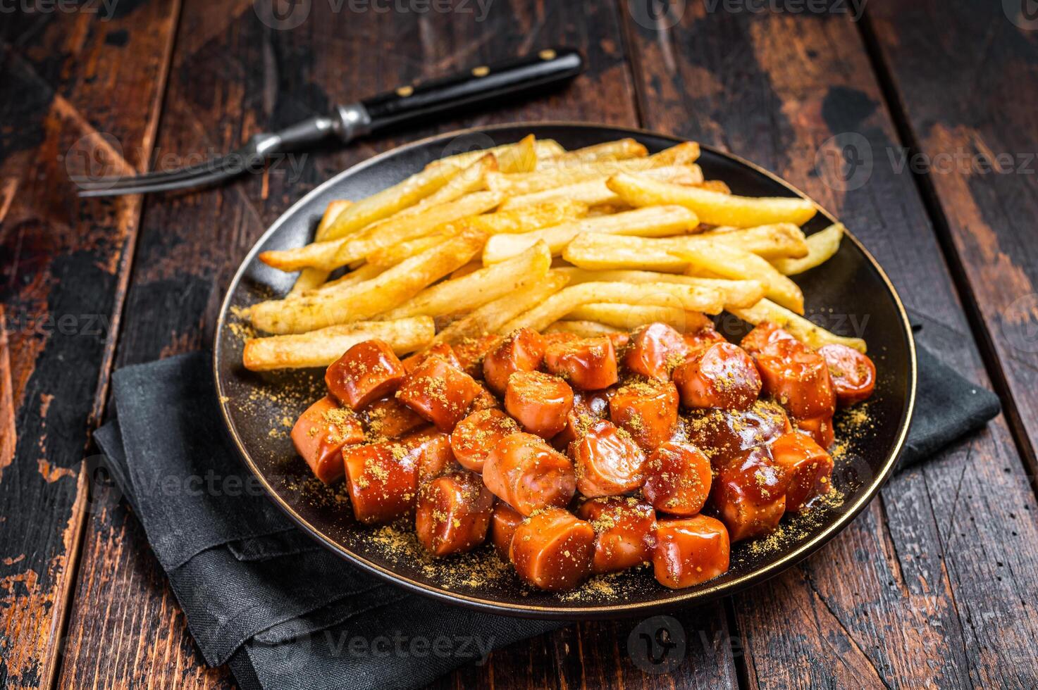 German currywurst meal, curry wurst with french fry served in a plate. Wooden background. Top view photo