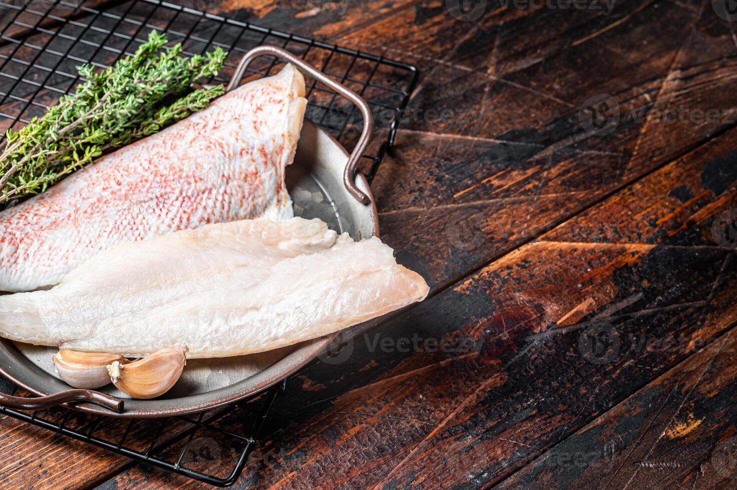 Raw red perch fillet, redfish fish meat in a steel tray. Wooden background. Top view. Copy space photo