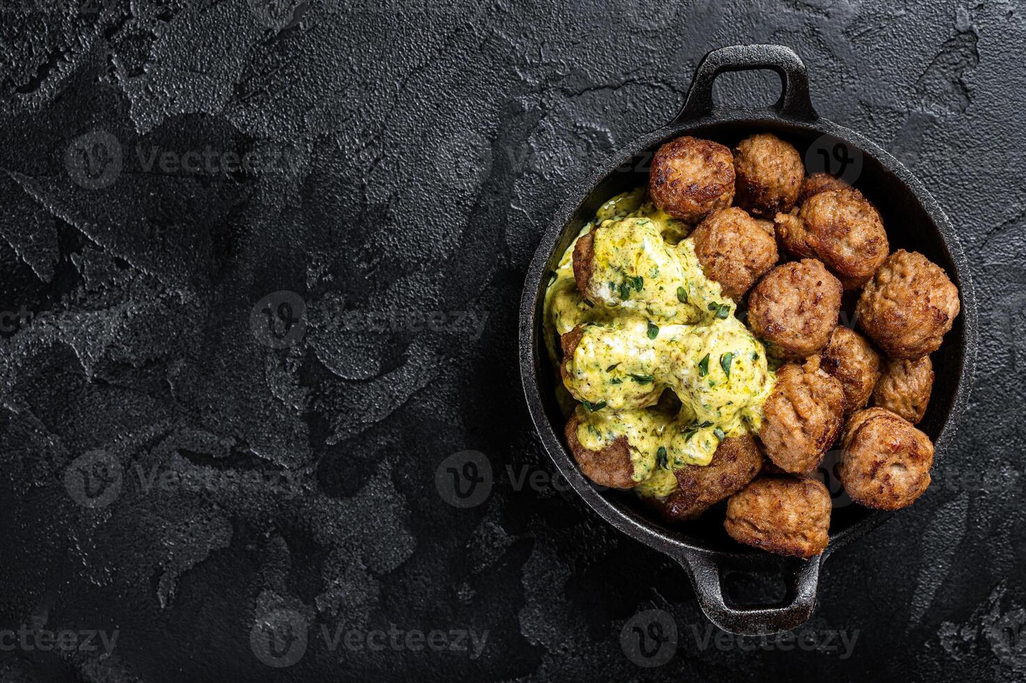 Skillet with Swedish beef Meatballs with Cream Sauce. Black background. Top view. Copy space photo