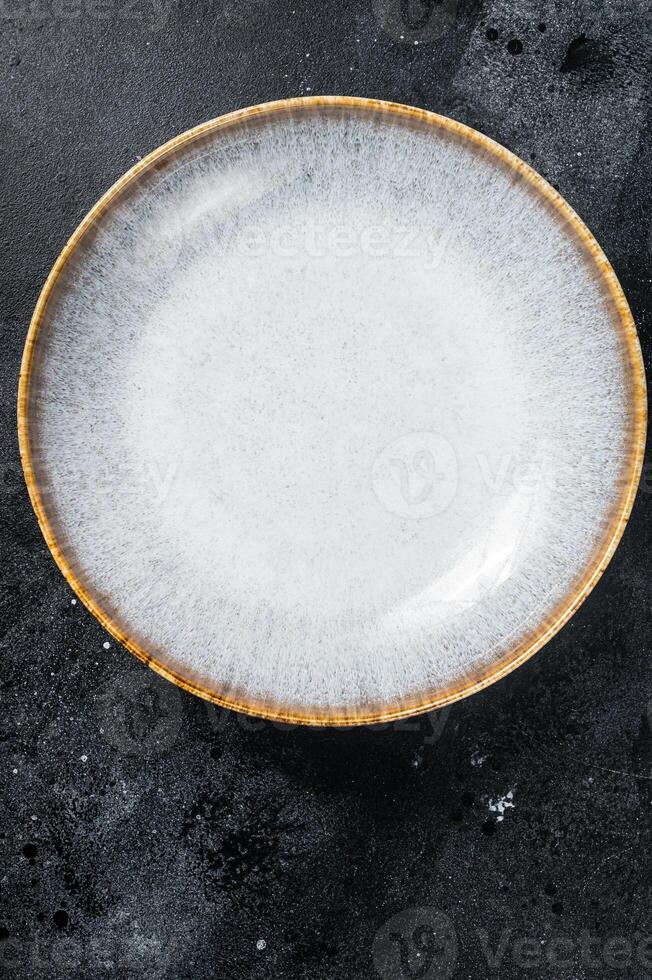 Food cooking background, empty white craft plate on table. Table setting. Black background. Top view. Copy space photo