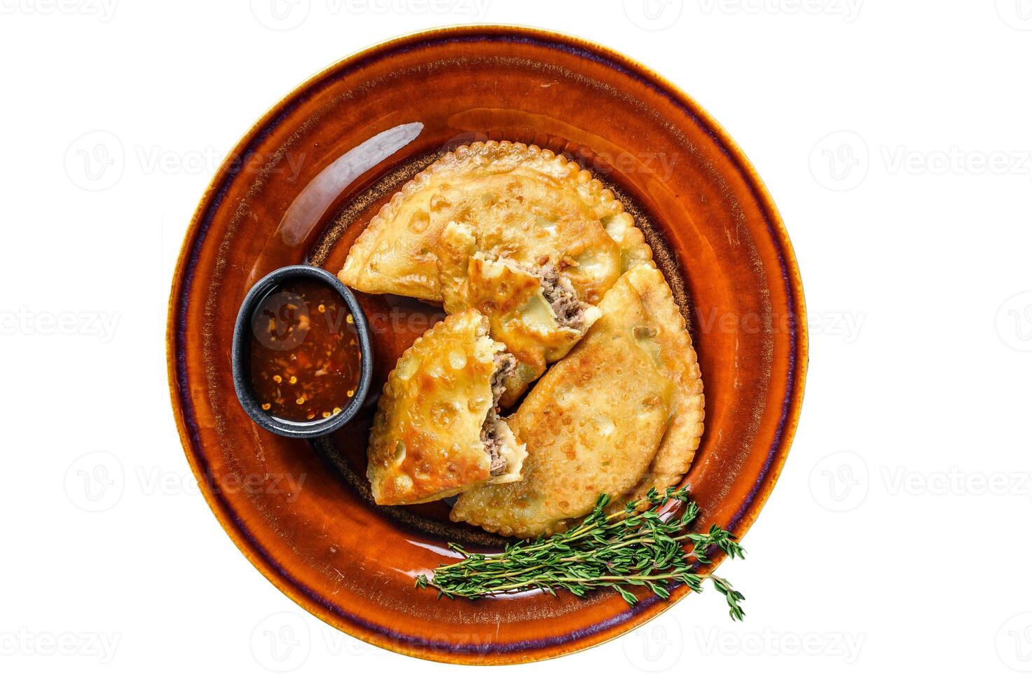 Fried empanadas with minced beef meat served on a plate with chili sauce. Isolated on white background. photo