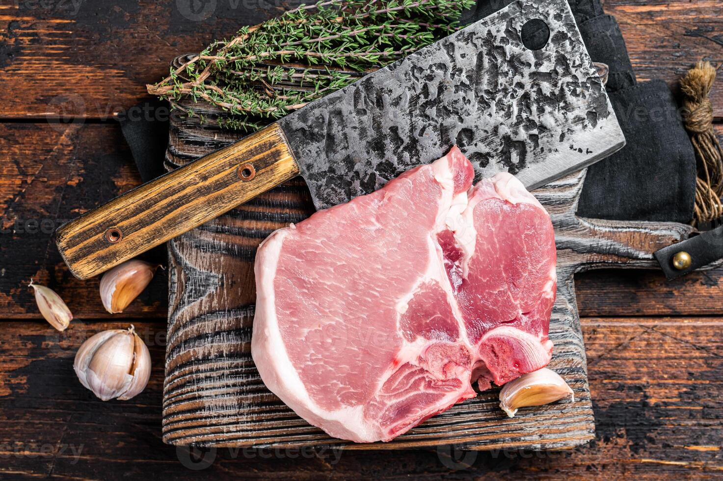 Butcher cutting board with Raw T-bone pork chop meat steak. Wooden background. Top view photo