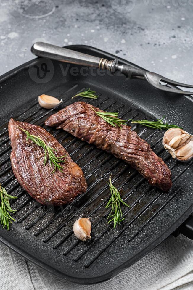 Roasted on a grill skillet Flank flap or Bavette beef meat steak with rosemary. Gray background. Top view photo