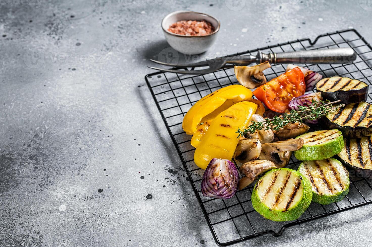 Seasonal summer Grilled vegetables on a grill, bell pepper, zucchini, eggplant, onion and tomato. Gray background. Top view. Copy space photo