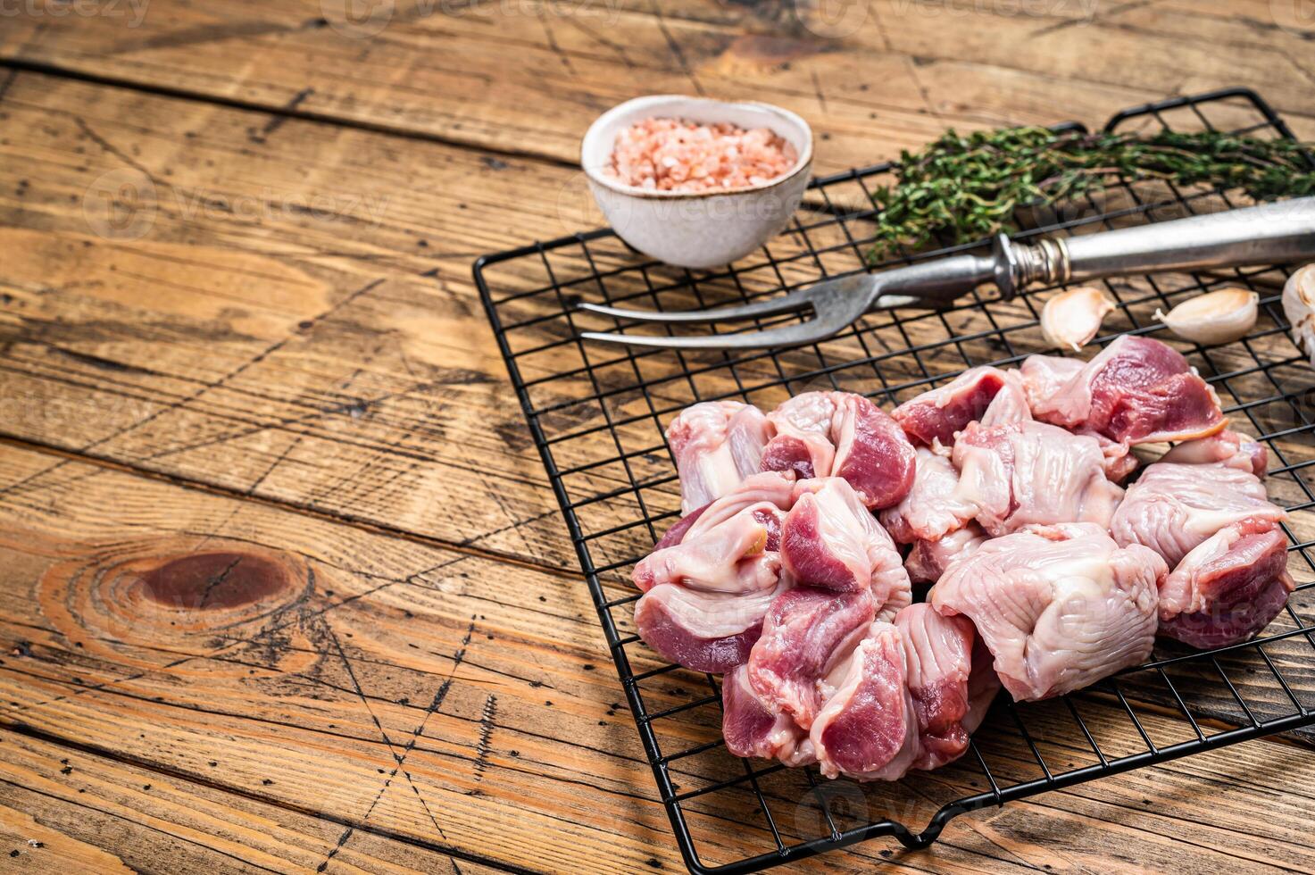 Fresh Raw chicken stomachs, gizzards on a grill ready for cooking with herbs. Wooden background. Top view. Copy space photo