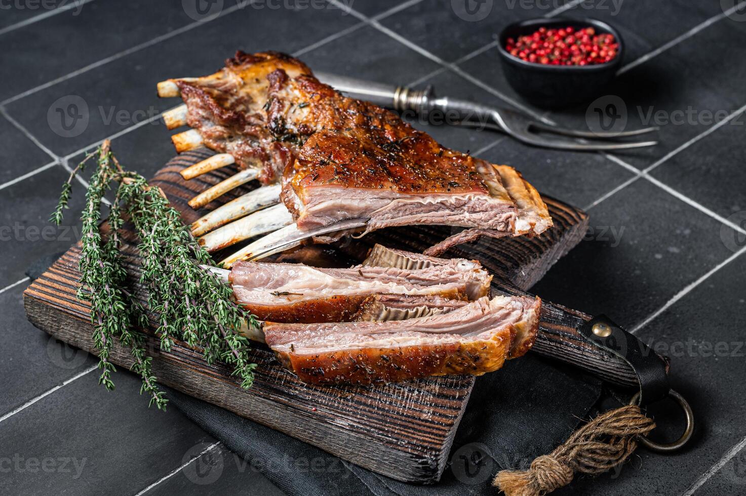 Grilled Rack of lamb ribs, mutton spareribs on wooden board. Black background. Top view photo