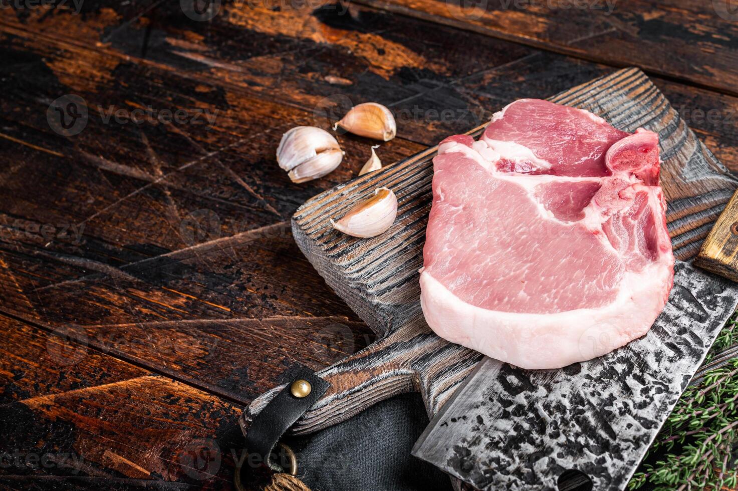 Butcher cutting board with Raw T-bone pork chop meat steak. Wooden background. Top view. Copy space photo