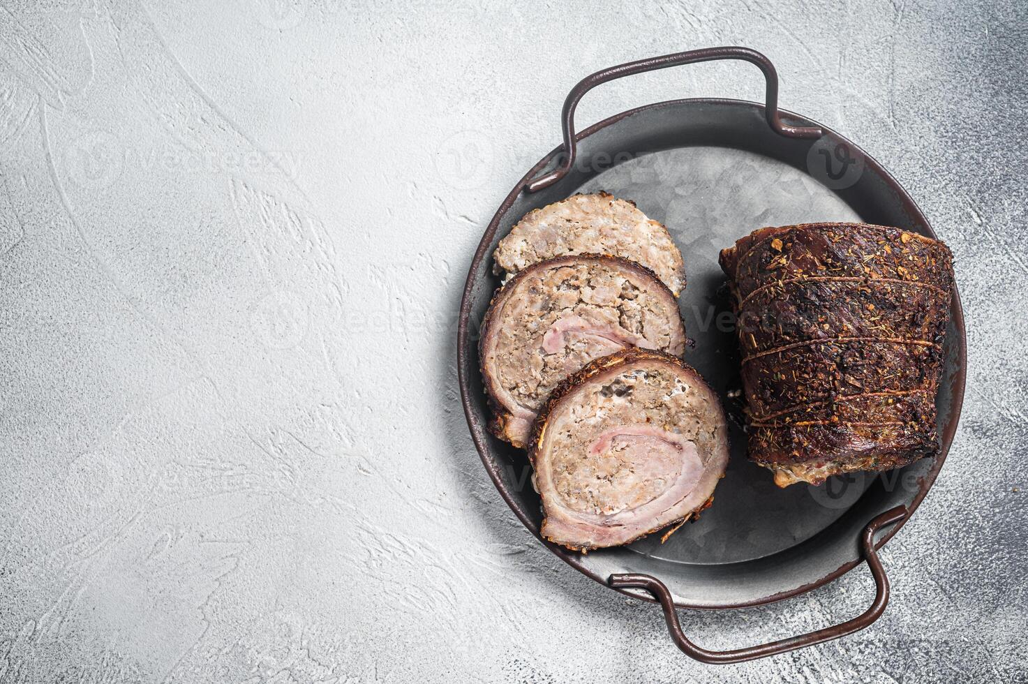 Sliced roast pork meat roulade on a steel tray. White background. Top view. Copy space photo