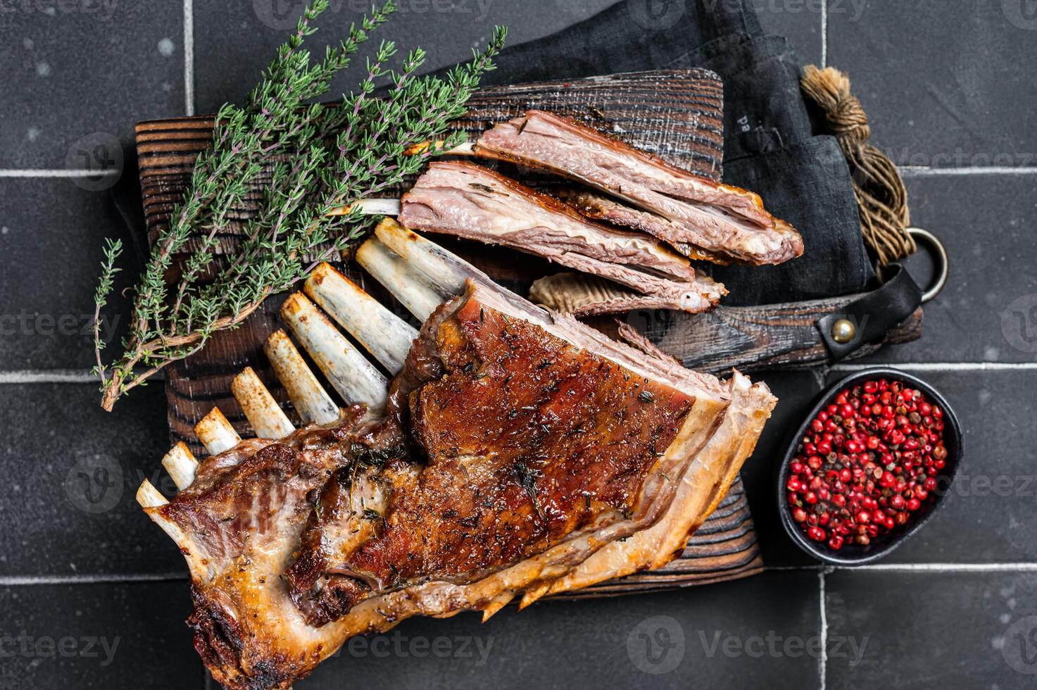 Grilled Rack of lamb ribs, mutton spareribs on wooden board. Black background. Top view photo