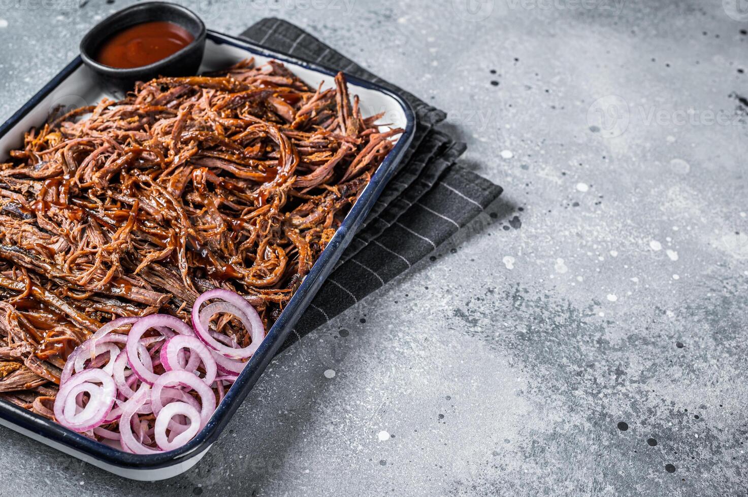 Pulled beef meat with hot chili sauce in baking dish. Gray background. Top view. Copy space photo