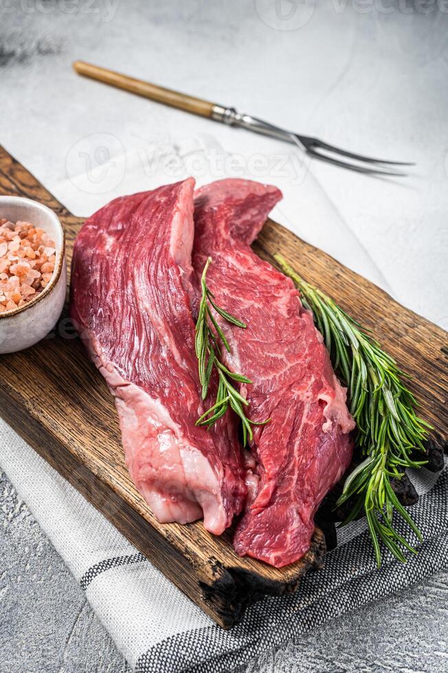 Butcher choise Bavette raw beef meat steak or flank flap on a wooden board with herbs. White background. Top view photo