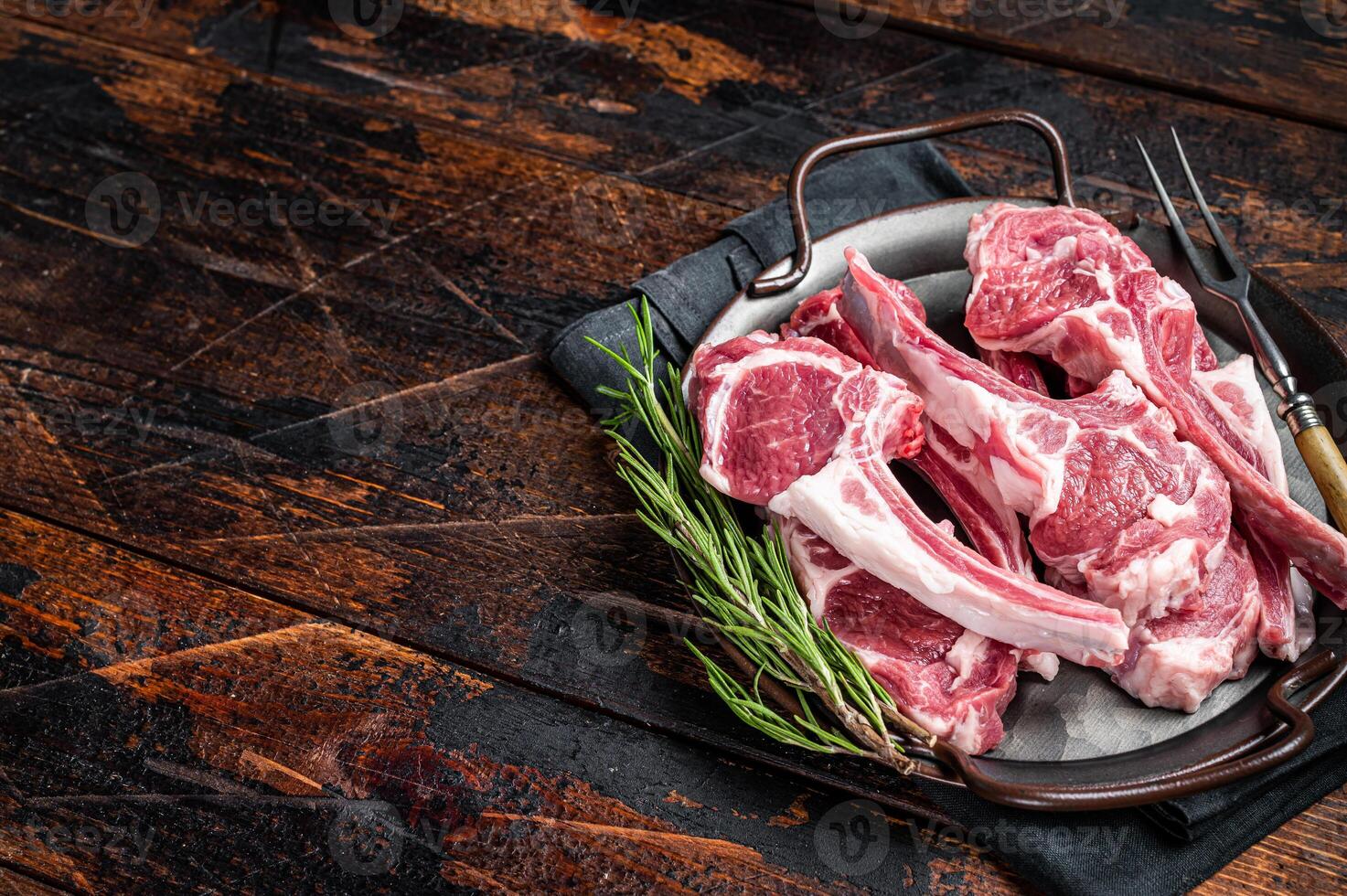 Raw lamb mutton chop steaks, fresh meat cutlets on butcher table. Black background. Top view. Copy space photo